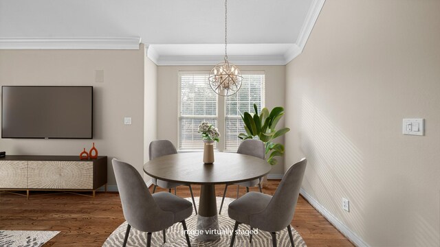dining room with baseboards, crown molding, wood finished floors, and a chandelier