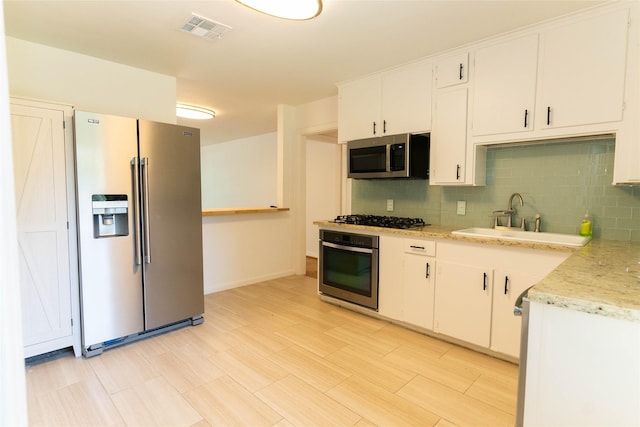 2315 Poinciana Dr, Houston, TX 77018 - kitchen featuring decorative backsplash, white cabinets, visible vents, stainless steel appliances, and a sink