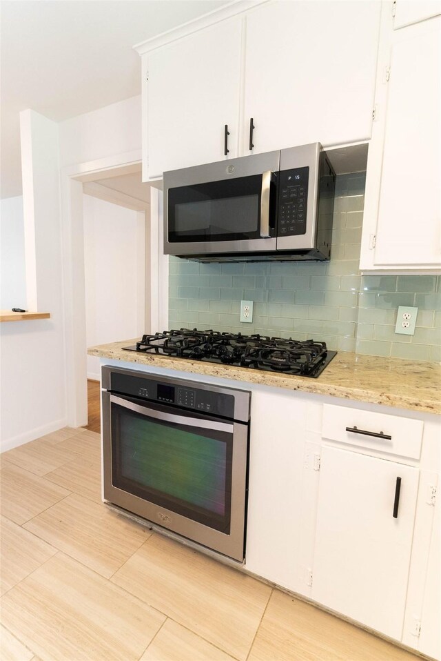 2315 Poinciana Dr, Houston, TX 77018 - kitchen featuring white cabinets, stainless steel appliances, tasteful backsplash, and light stone counters