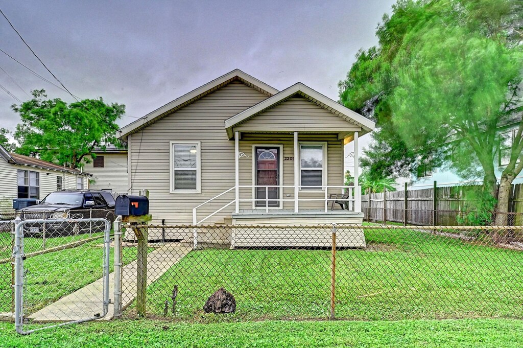 view of front facade featuring covered porch, fence, a front lawn, and a gate