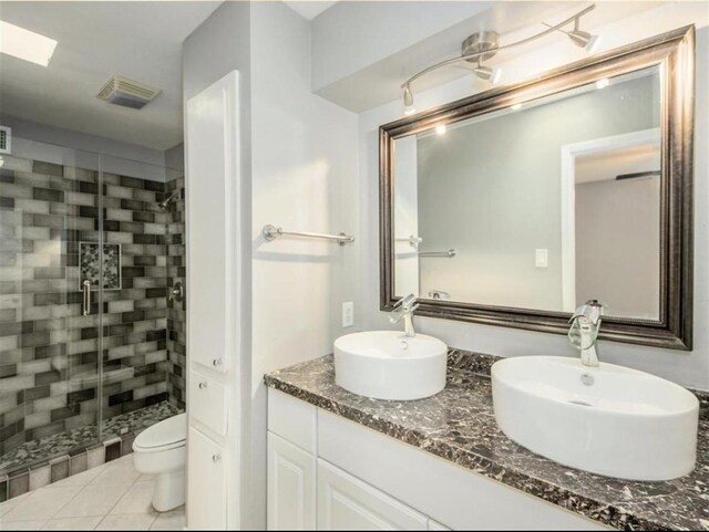 bathroom with a shower stall, double vanity, a sink, and toilet
