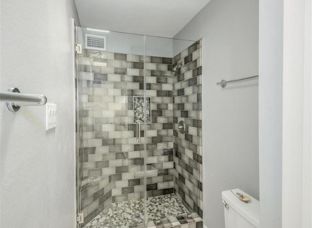bathroom featuring toilet, a stall shower, and visible vents