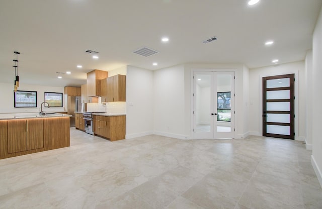 kitchen with brown cabinets, visible vents, french doors, and high end range