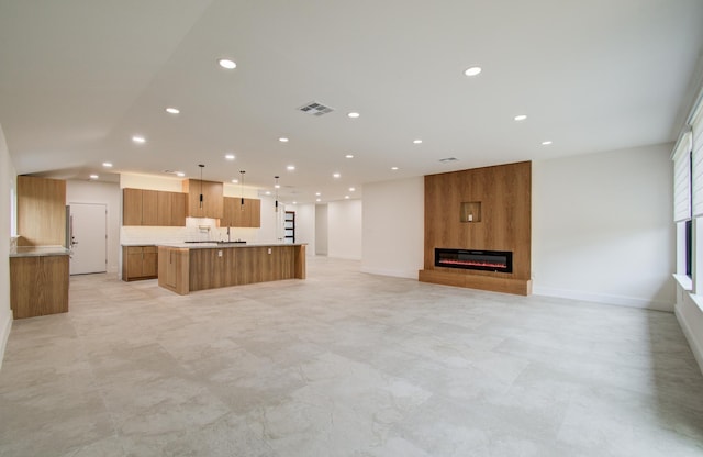 interior space featuring light countertops, a large fireplace, recessed lighting, open floor plan, and a large island with sink