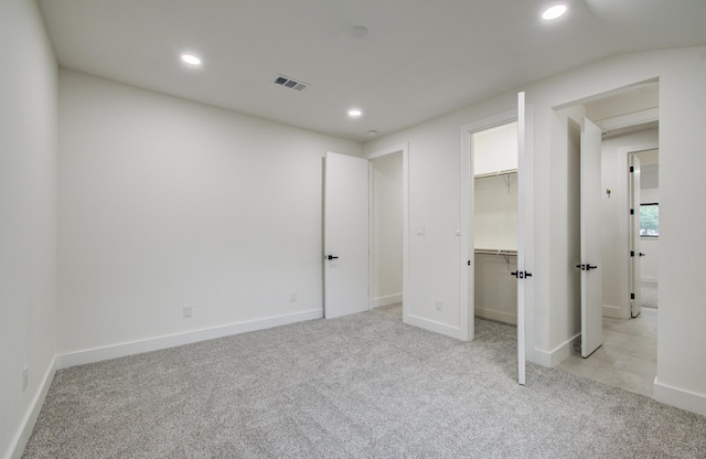 unfurnished bedroom with light colored carpet, visible vents, a spacious closet, and recessed lighting