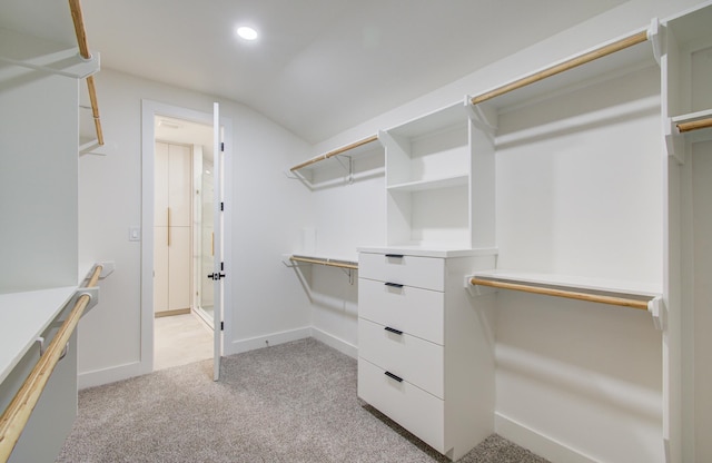 walk in closet with light colored carpet and vaulted ceiling