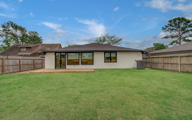 back of house featuring central air condition unit, a lawn, and a fenced backyard