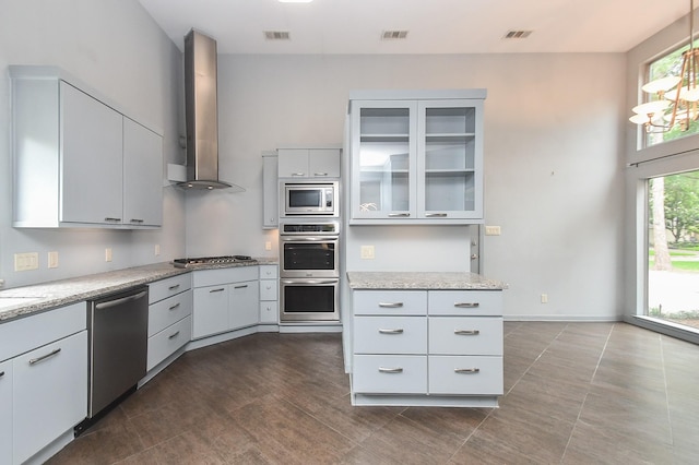 2918 Manila Ln, Houston, TX 77043 - kitchen featuring appliances with stainless steel finishes, wall chimney exhaust hood, glass insert cabinets, light stone counters, and pendant lighting