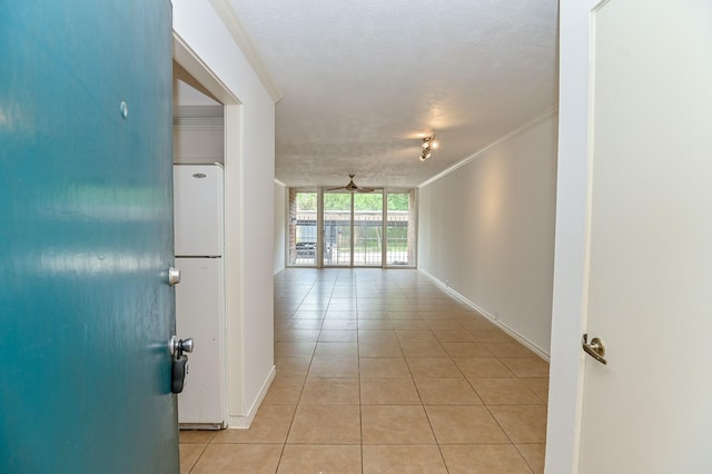 hall featuring light tile patterned flooring, a textured ceiling, and crown molding