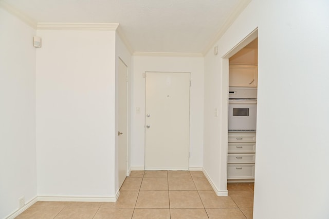 corridor featuring light tile patterned flooring, baseboards, and crown molding