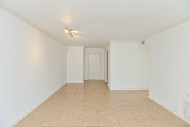 spare room featuring baseboards, ornamental molding, visible vents, and light tile patterned floors