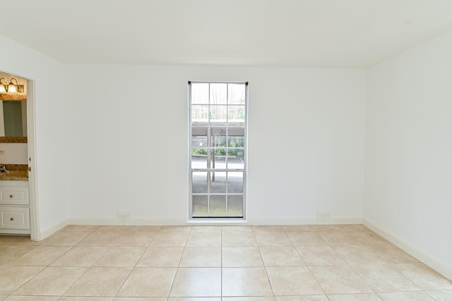 empty room with baseboards and light tile patterned floors