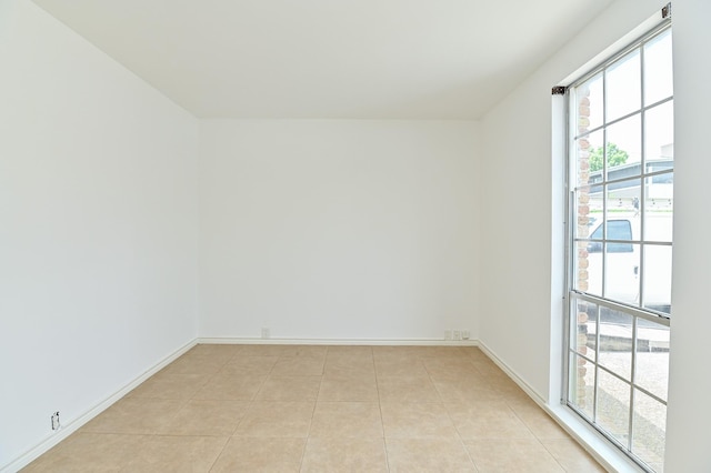 spare room featuring light tile patterned floors and baseboards