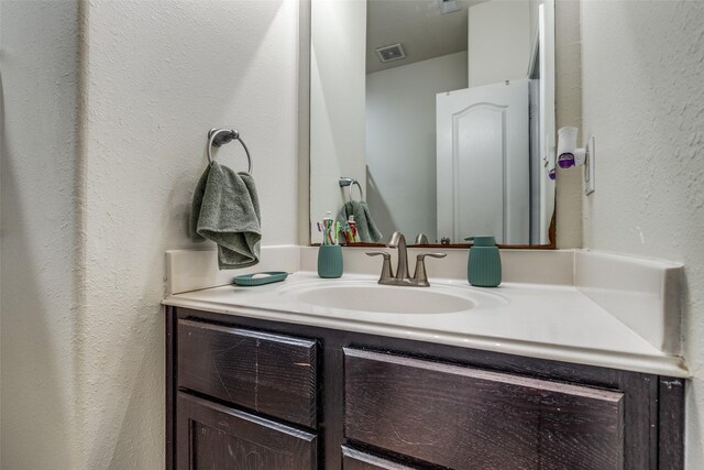 bathroom featuring visible vents, a textured wall, and vanity