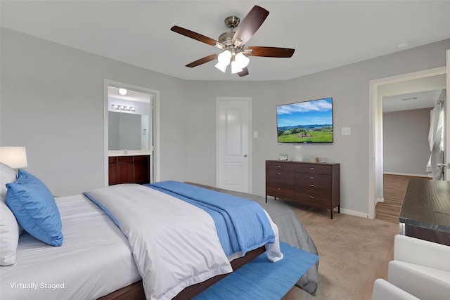 bedroom with light colored carpet, baseboards, a ceiling fan, and ensuite bathroom