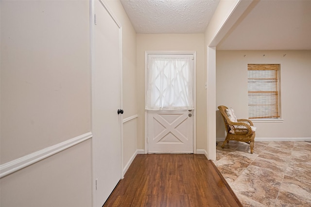 entryway featuring a textured ceiling and baseboards