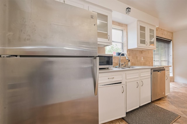kitchen featuring a sink, stainless steel appliances, decorative backsplash, white cabinetry, and light countertops