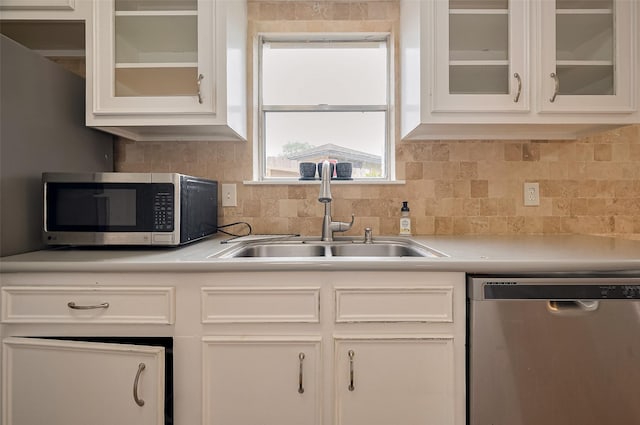 kitchen with white cabinets, stainless steel appliances, light countertops, and a sink