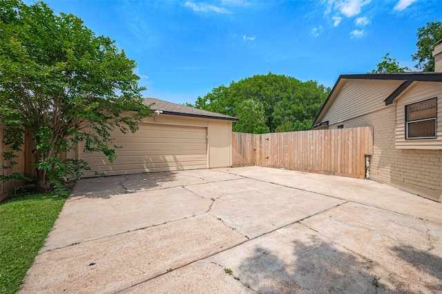 exterior space with fence, concrete driveway, and a garage