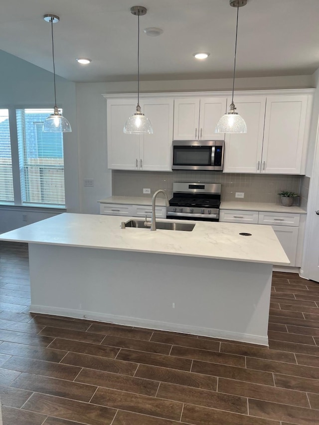26767 Grandiflora Dr, Magnolia, TX 77355 - kitchen with tasteful backsplash, hanging light fixtures, a sink, wood finish floors, and stainless steel appliances