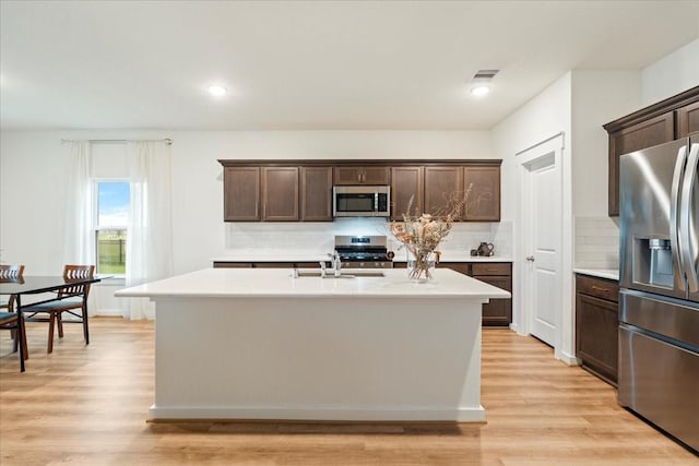 kitchen with dark brown cabinetry, light countertops, a sink, and stainless steel appliances