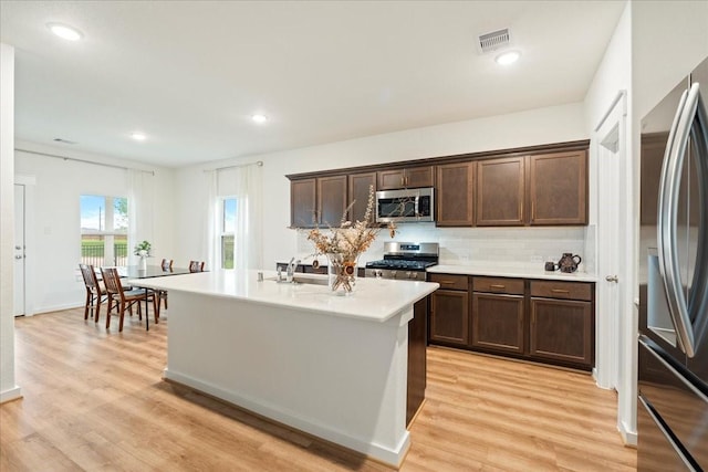 kitchen with light countertops, stainless steel appliances, visible vents, light wood-style floors, and dark brown cabinets