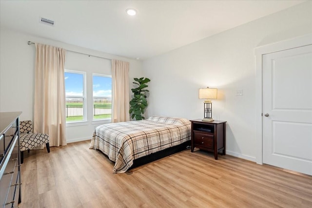 bedroom with baseboards, visible vents, and light wood-type flooring