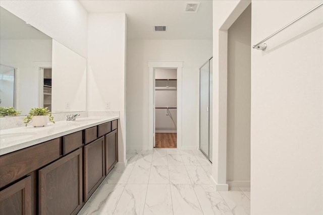 bathroom with marble finish floor, a spacious closet, and a shower stall