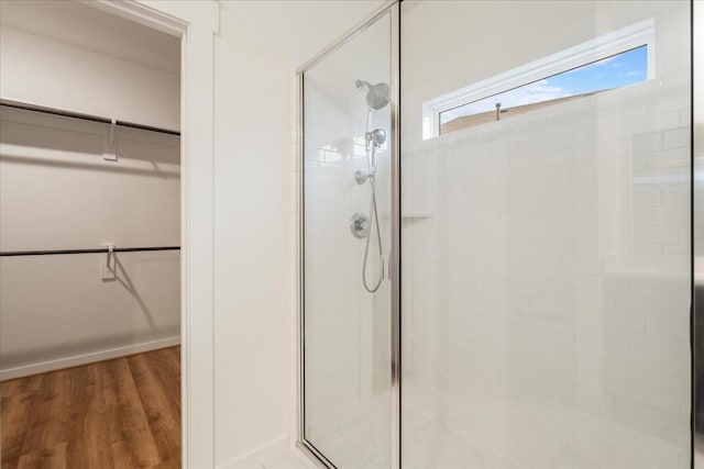 bathroom featuring a stall shower, wood finished floors, and a spacious closet