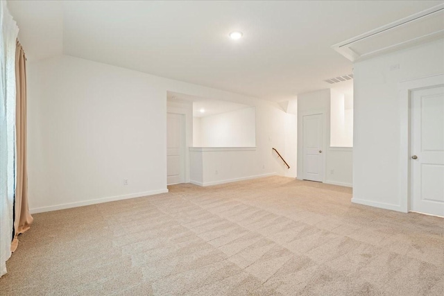 unfurnished room with light carpet, baseboards, attic access, and visible vents