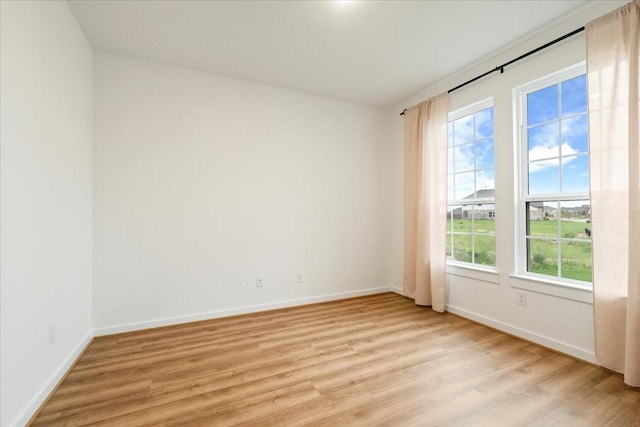 unfurnished room with baseboards and light wood finished floors