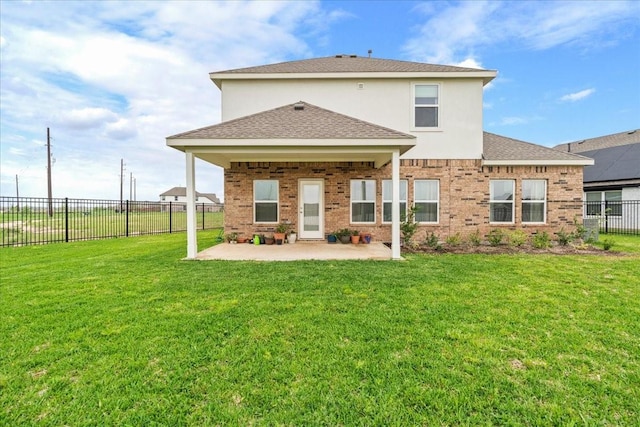 back of property featuring fence, roof with shingles, a yard, and a patio area