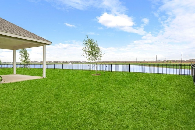 view of yard featuring a water view, fence, and a patio area