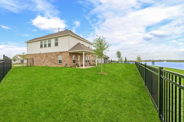 view of yard with a water view, a fenced backyard, and a patio area