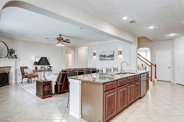 kitchen with arched walkways, a sink, dishwasher, light tile patterned floors, and recessed lighting