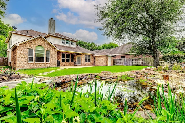 back of house featuring a garden pond, brick siding, and a chimney