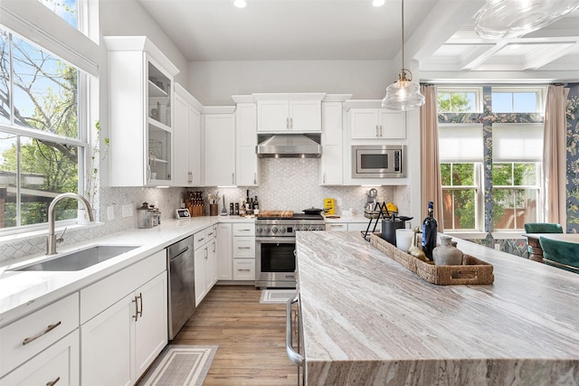 4504 Yupon St, Houston, TX 77006 - kitchen with stainless steel appliances, a sink, under cabinet range hood, light stone counters, and white cabinets