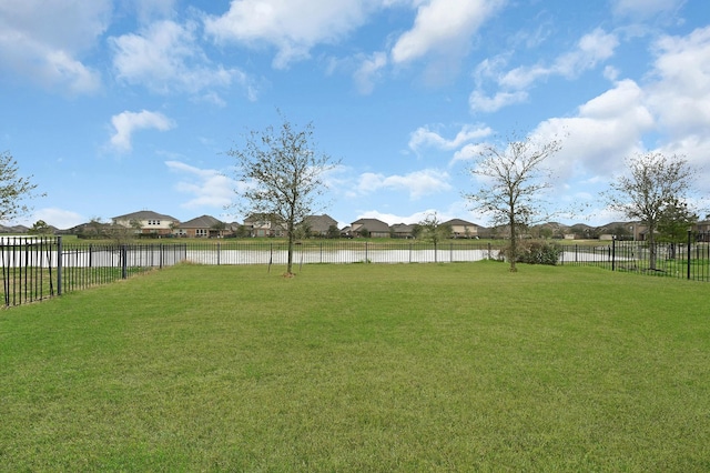 view of yard with a water view, fence, and a residential view