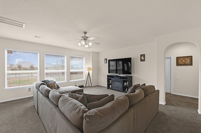 living room featuring arched walkways, carpet flooring, and visible vents