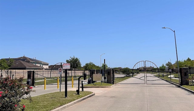 view of road featuring a gated entry, curbs, and a gate