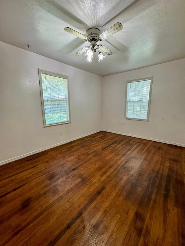 447 Fm 2540 N, Van Vleck, TX 77482 - spare room with dark wood-style floors, healthy amount of natural light, ceiling fan, baseboards, and a textured ceiling
