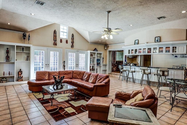 tiled living room with lofted ceiling, french doors, visible vents, and a textured ceiling