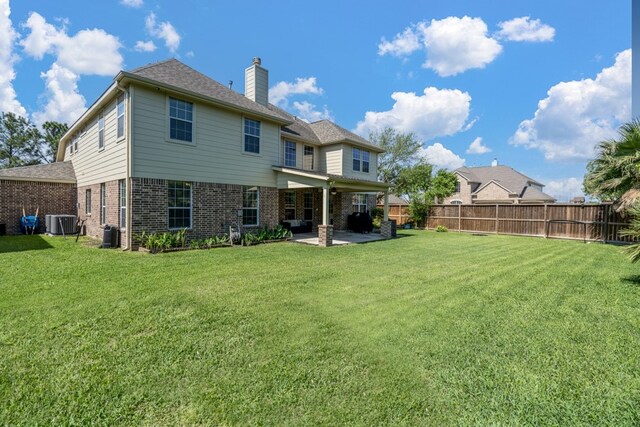 back of house with brick siding, a patio area, central AC, and a chimney