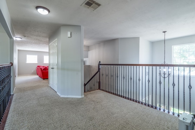 hall featuring carpet flooring, baseboards, and an upstairs landing