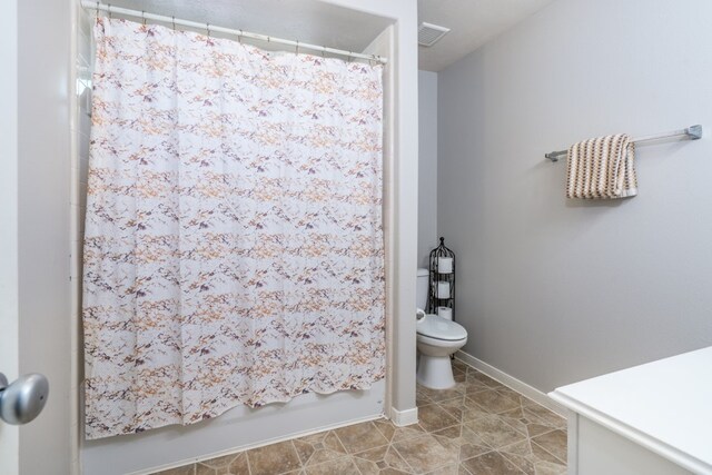 bathroom with toilet, a shower with curtain, baseboards, and tile patterned floors