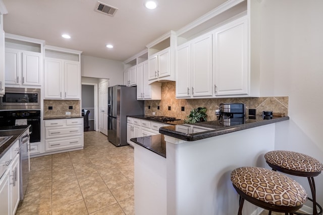 kitchen featuring appliances with stainless steel finishes, decorative backsplash, white cabinetry, and recessed lighting