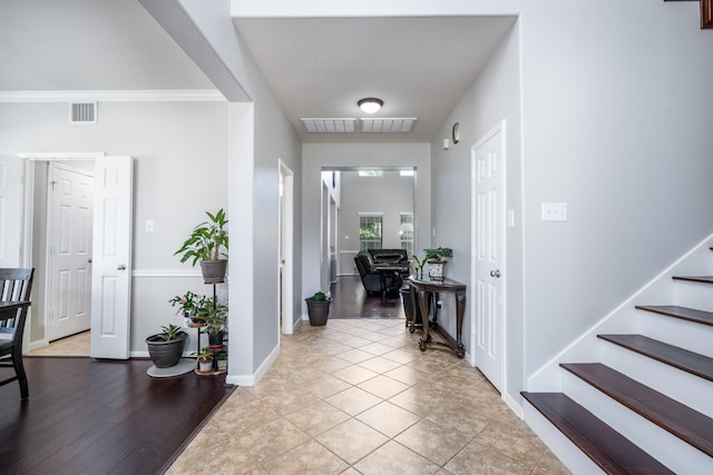 foyer featuring stairs, baseboards, and light tile patterned floors