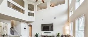 living area with arched walkways, a high ceiling, and a ceiling fan