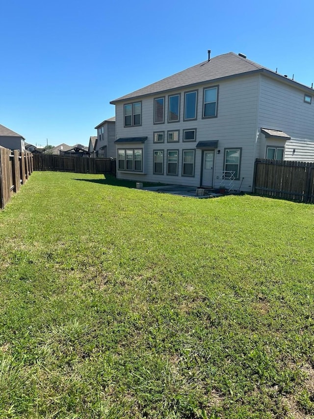rear view of property with a yard and a fenced backyard