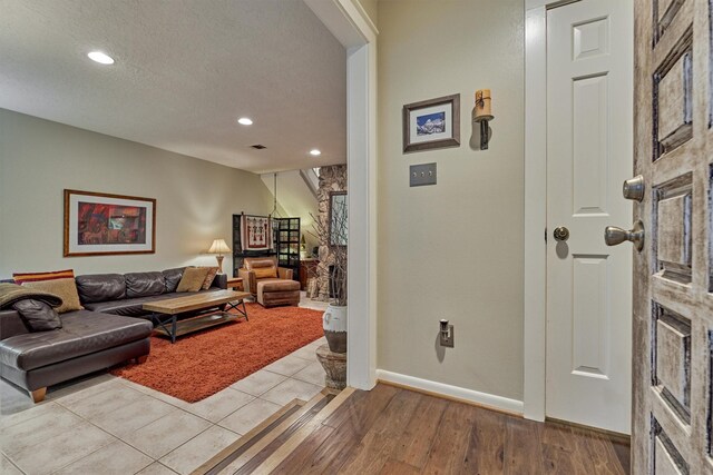 living area featuring a textured ceiling, wood finished floors, baseboards, and recessed lighting